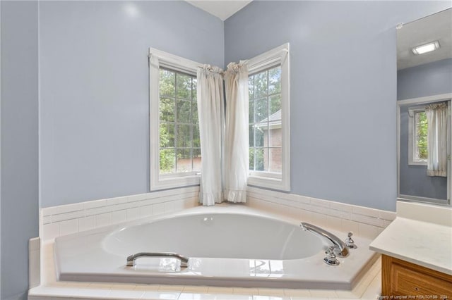 bathroom with tiled tub and vanity