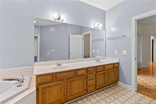 bathroom with tiled tub, vanity, and parquet floors