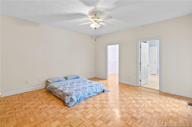 bedroom with ceiling fan, a textured ceiling, a walk in closet, and light parquet floors