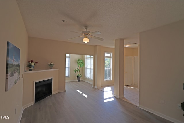 unfurnished living room featuring ceiling fan, light hardwood / wood-style flooring, and a textured ceiling