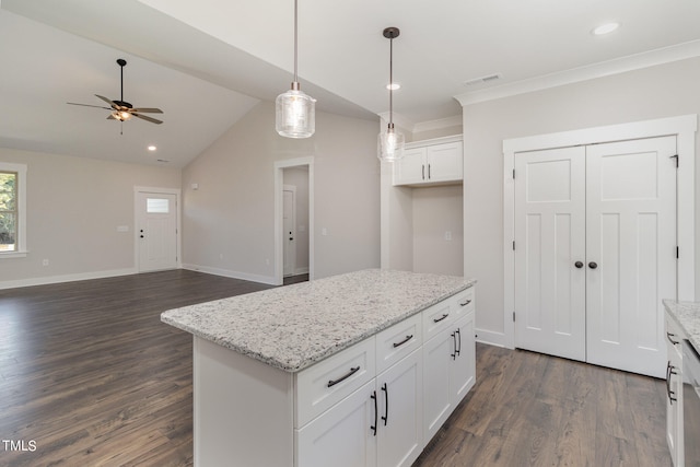 kitchen featuring decorative light fixtures, light stone countertops, white cabinets, and a kitchen island