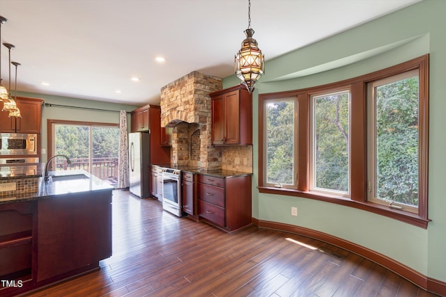 kitchen with pendant lighting, backsplash, sink, dark hardwood / wood-style flooring, and stainless steel appliances