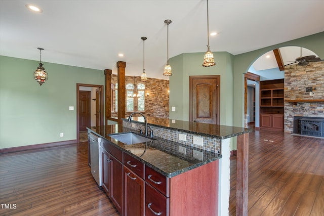 kitchen with dark hardwood / wood-style floors, decorative light fixtures, a kitchen island with sink, and sink