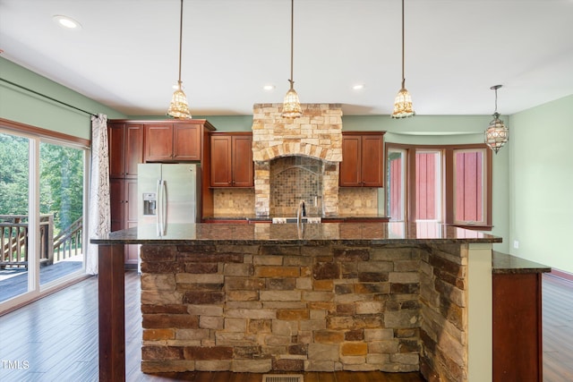 3240 Hillcastle Trl, Chapel Hill, NC 27516 - kitchen with stainless steel fridge, dark wood-style flooring, tasteful backsplash, a kitchen island with sink, and dark stone countertops