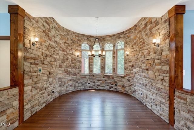 unfurnished dining area featuring a chandelier and dark hardwood / wood-style flooring