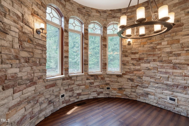 spare room featuring an inviting chandelier and dark wood-type flooring