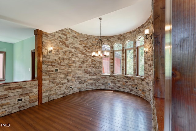 unfurnished dining area featuring wood-type flooring and an inviting chandelier