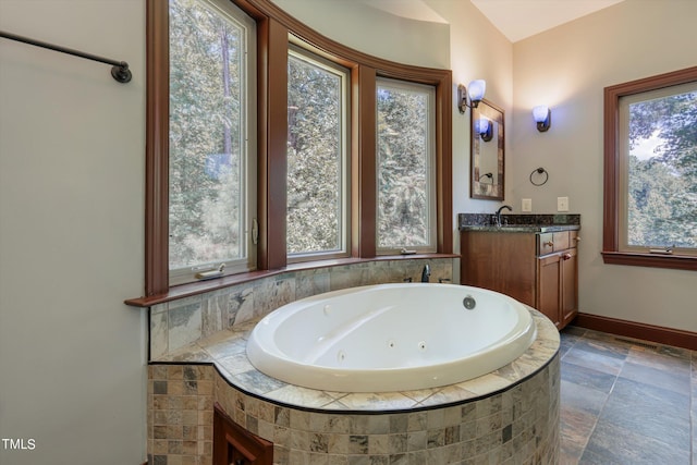 bathroom with vanity, tiled bath, and a wealth of natural light