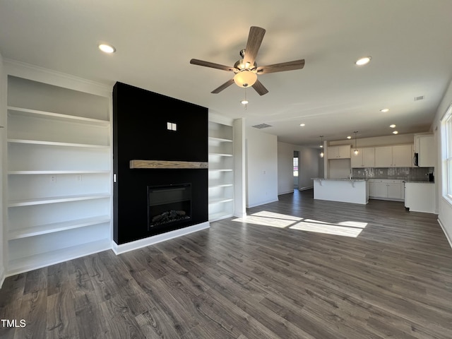 unfurnished living room with dark hardwood / wood-style floors, ceiling fan, and built in shelves