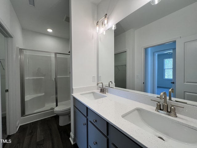 bathroom featuring wood-type flooring, toilet, a shower with shower door, and vanity