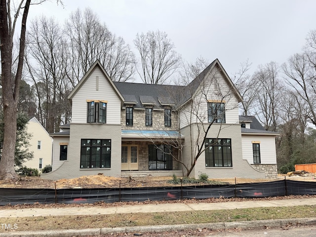 back of house with stone siding, brick siding, and fence