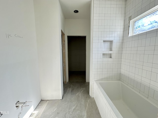 full bath with a relaxing tiled tub and marble finish floor