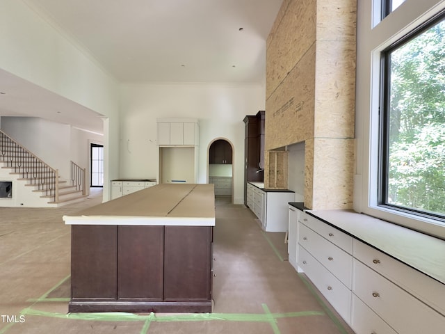 7208 Tanbark Way, Raleigh, NC 27615 - kitchen featuring a center island, ornamental molding, a high ceiling, and white cabinets