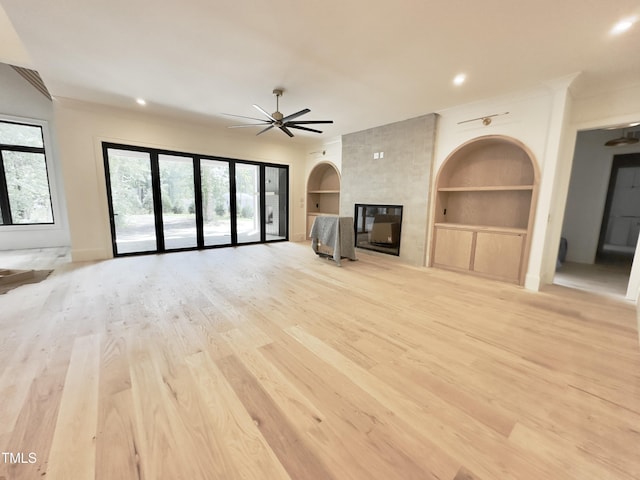 7208 Tanbark Way, Raleigh, NC 27615 - unfurnished living room featuring built in features, a ceiling fan, light wood-style flooring, a large fireplace, and baseboards