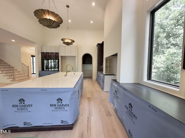 7208 Tanbark Way, Raleigh, NC 27615 - kitchen featuring a sink, light wood-style floors, a high ceiling, white cabinetry, and a center island with sink