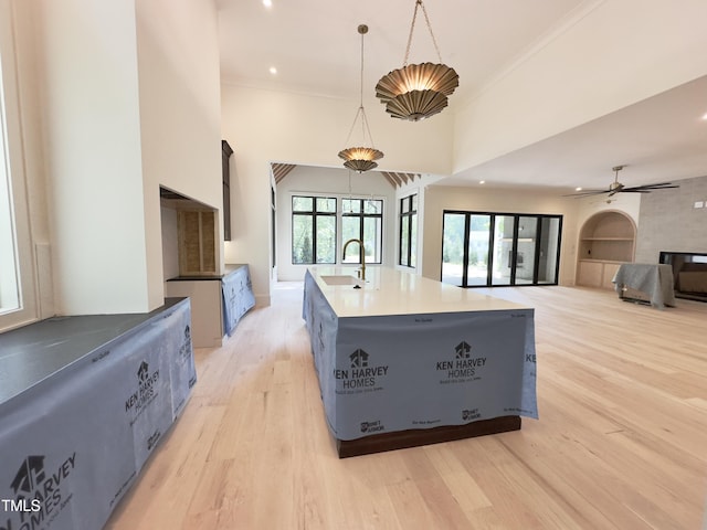 7208 Tanbark Way, Raleigh, NC 27615 - kitchen featuring light wood-type flooring, a kitchen island with sink, pendant lighting, light countertops, and ceiling fan