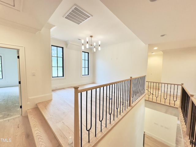 7208 Tanbark Way, Raleigh, NC 27615 - hallway featuring a chandelier, wood finished floors, crown molding, and an upstairs landing