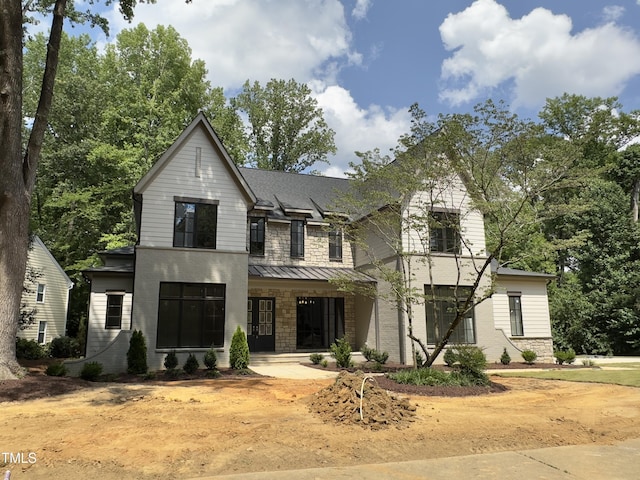 7208 Tanbark Way, Raleigh, NC 27615 - view of front of home with stone siding, a standing seam roof, a porch, and a metal roof