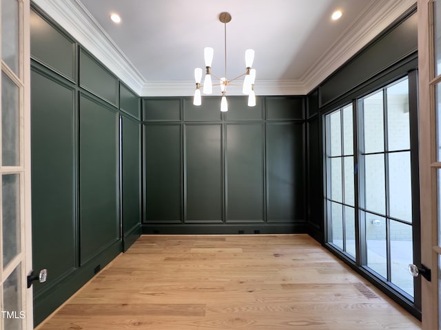 7208 Tanbark Way, Raleigh, NC 27615 - unfurnished dining area featuring a decorative wall, plenty of natural light, crown molding, a chandelier, and light wood-type flooring