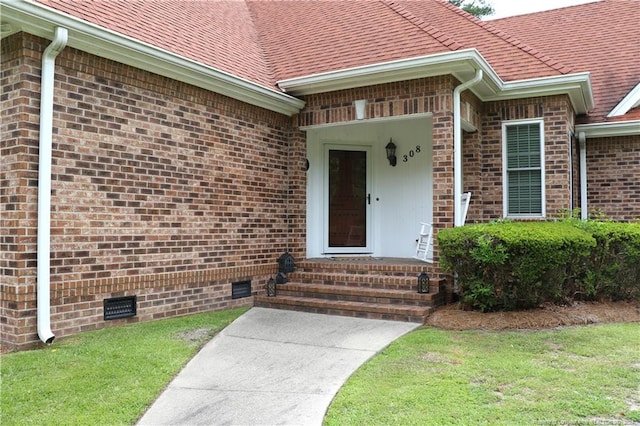 view of exterior entry featuring a lawn