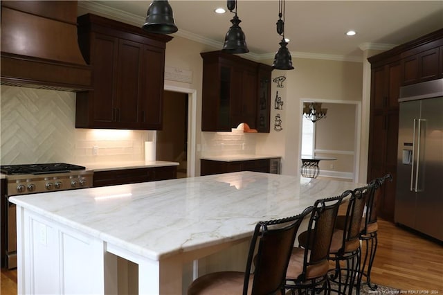 kitchen with light hardwood / wood-style floors, custom exhaust hood, a center island, high end appliances, and decorative backsplash