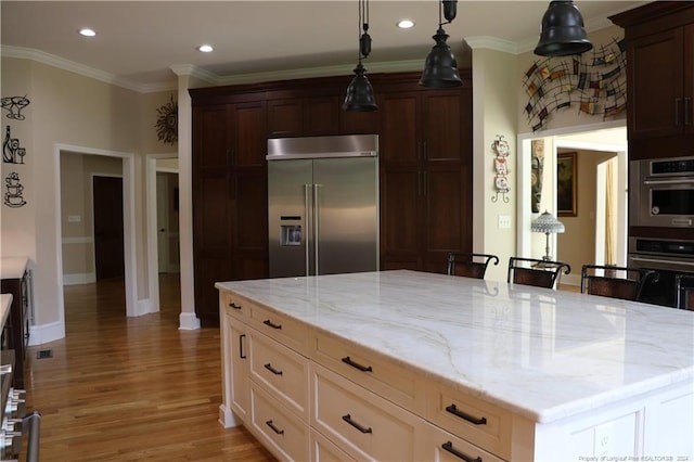 kitchen featuring appliances with stainless steel finishes, light hardwood / wood-style flooring, light stone counters, and a center island