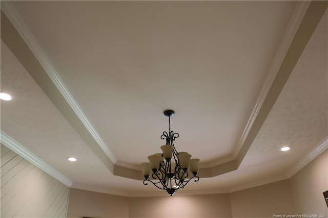 details featuring ornamental molding, a chandelier, and a raised ceiling