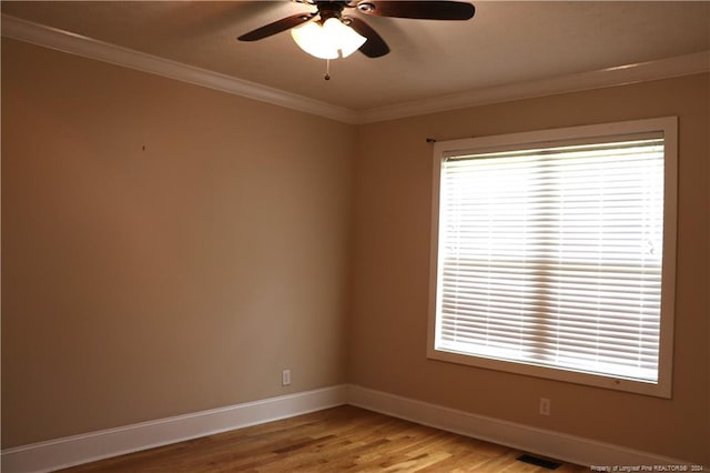 empty room with ceiling fan, wood-type flooring, plenty of natural light, and ornamental molding