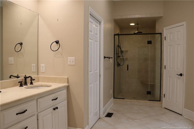 bathroom featuring a shower with shower door, vanity, and tile patterned floors