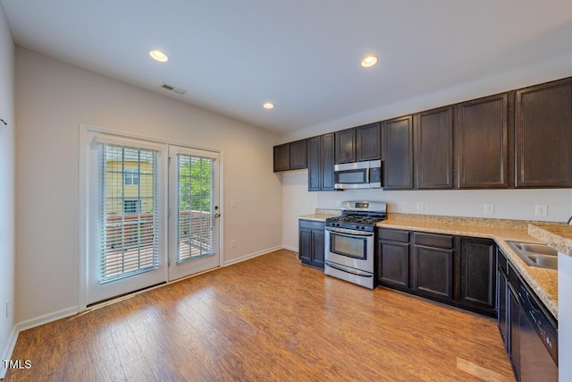 kitchen with dark brown cabinetry, stainless steel appliances, sink, and light hardwood / wood-style floors