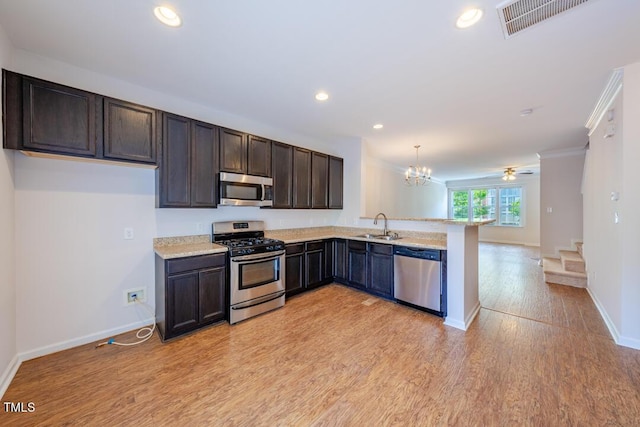 kitchen featuring pendant lighting, sink, light hardwood / wood-style flooring, stainless steel appliances, and kitchen peninsula