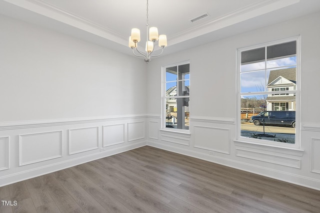 spare room featuring wood-type flooring, a tray ceiling, and a chandelier