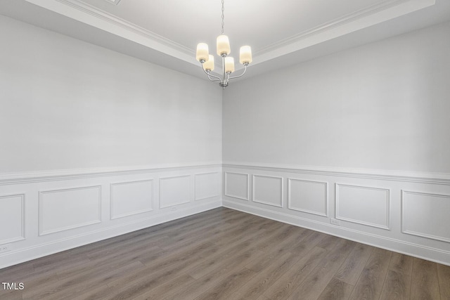 spare room featuring dark wood-type flooring and an inviting chandelier