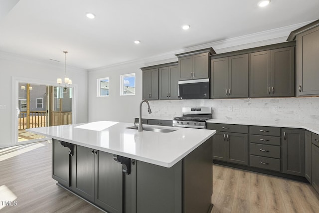 kitchen featuring light hardwood / wood-style flooring, a center island with sink, stainless steel range, crown molding, and sink