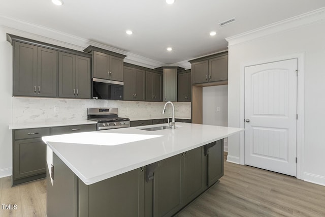 kitchen with sink, ornamental molding, a kitchen island with sink, and stainless steel gas range