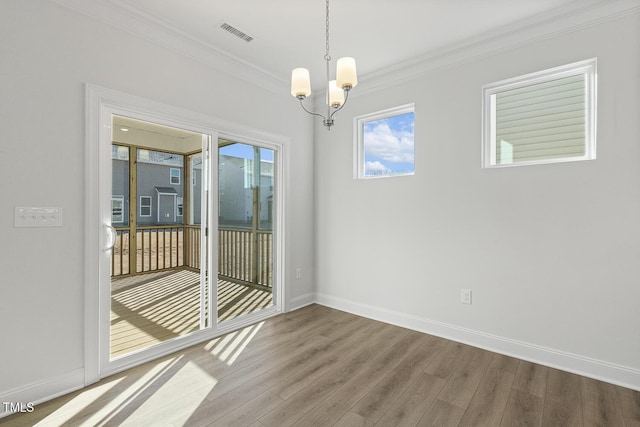 spare room with ornamental molding, a notable chandelier, and hardwood / wood-style flooring