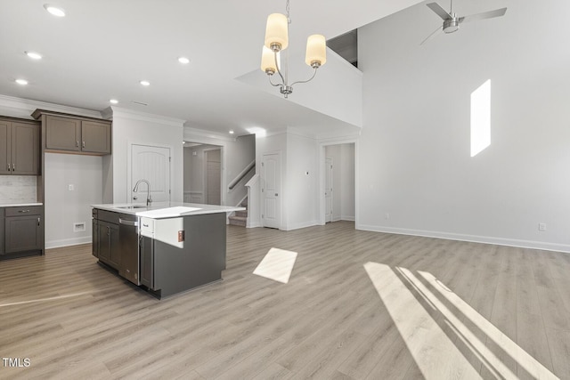 kitchen featuring dishwasher, a kitchen island with sink, sink, light hardwood / wood-style flooring, and ceiling fan with notable chandelier