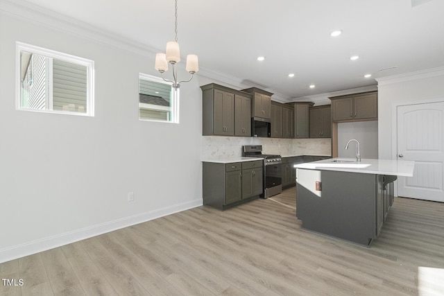 kitchen featuring a center island with sink, gas stove, ornamental molding, decorative backsplash, and sink