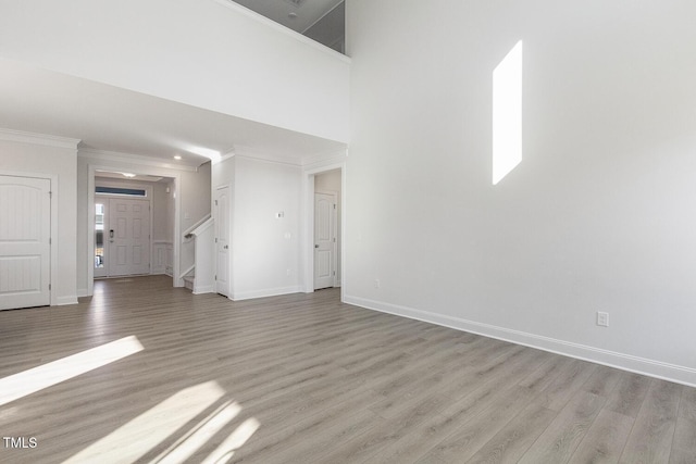 unfurnished living room featuring light wood-type flooring and ornamental molding