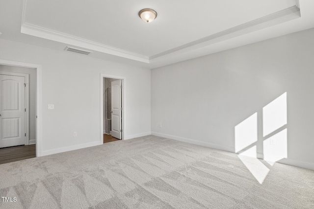 unfurnished room with ornamental molding, light carpet, and a raised ceiling