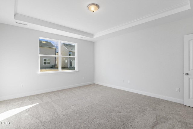 carpeted spare room with ornamental molding and a raised ceiling