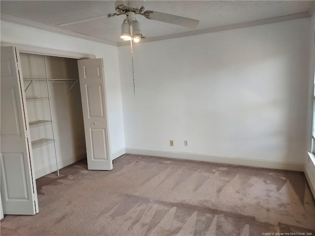 unfurnished bedroom featuring ceiling fan, light colored carpet, ornamental molding, and a closet