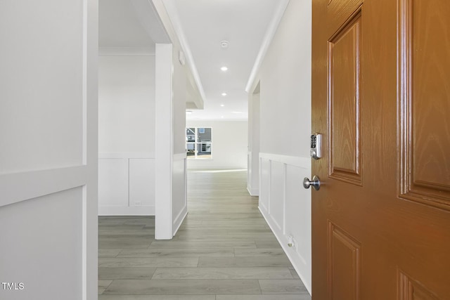 hallway with ornamental molding and light hardwood / wood-style floors