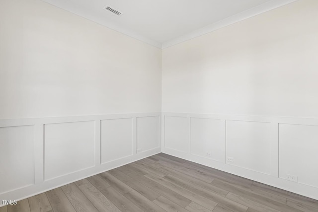 spare room featuring light wood-type flooring and ornamental molding