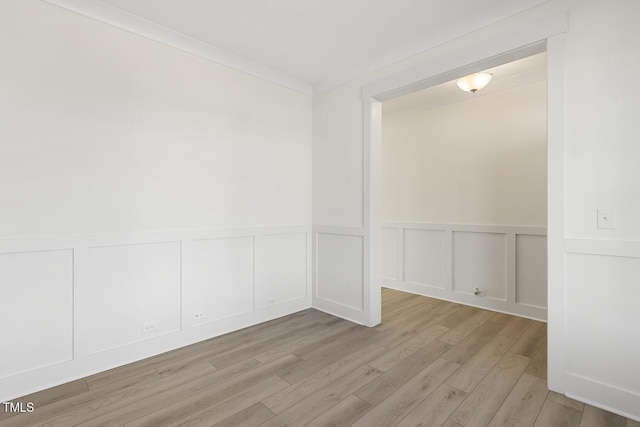 empty room with ornamental molding and light hardwood / wood-style floors