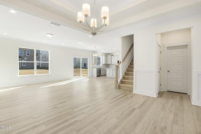 unfurnished living room featuring a notable chandelier and light hardwood / wood-style flooring