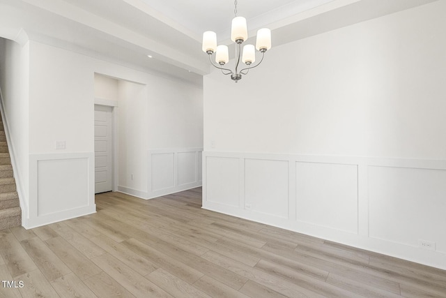 spare room with ornamental molding, light hardwood / wood-style flooring, and a chandelier