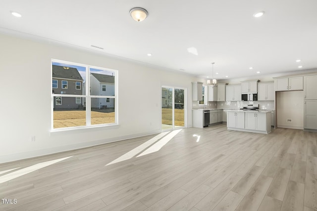 unfurnished living room with light hardwood / wood-style floors, crown molding, and a chandelier