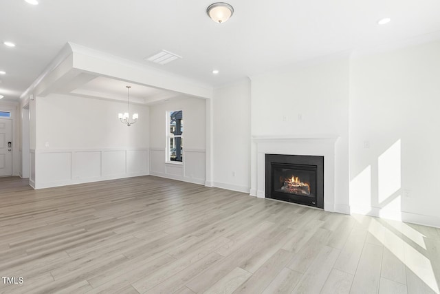 unfurnished living room featuring light wood-type flooring, a notable chandelier, crown molding, and a tray ceiling