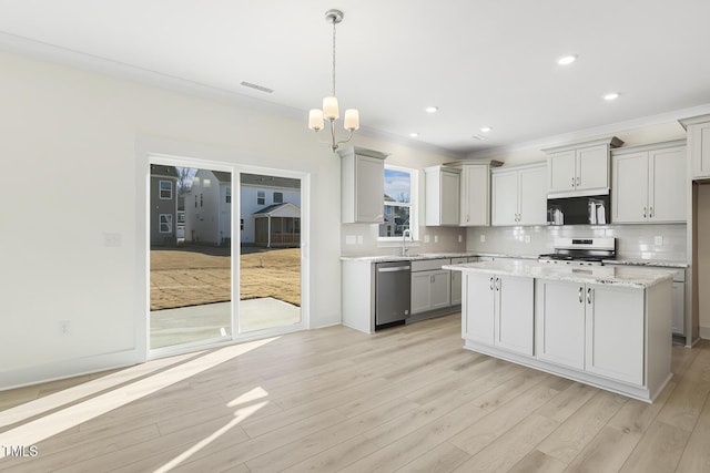 kitchen featuring stainless steel appliances, a center island, light hardwood / wood-style floors, and hanging light fixtures